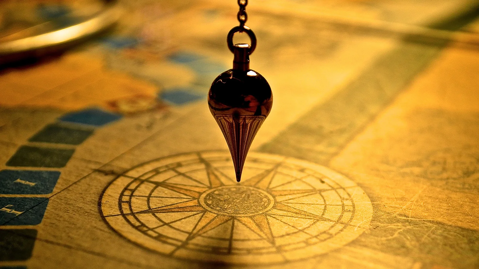 Metal plumb bob hanging over compass rose printed on vintage map