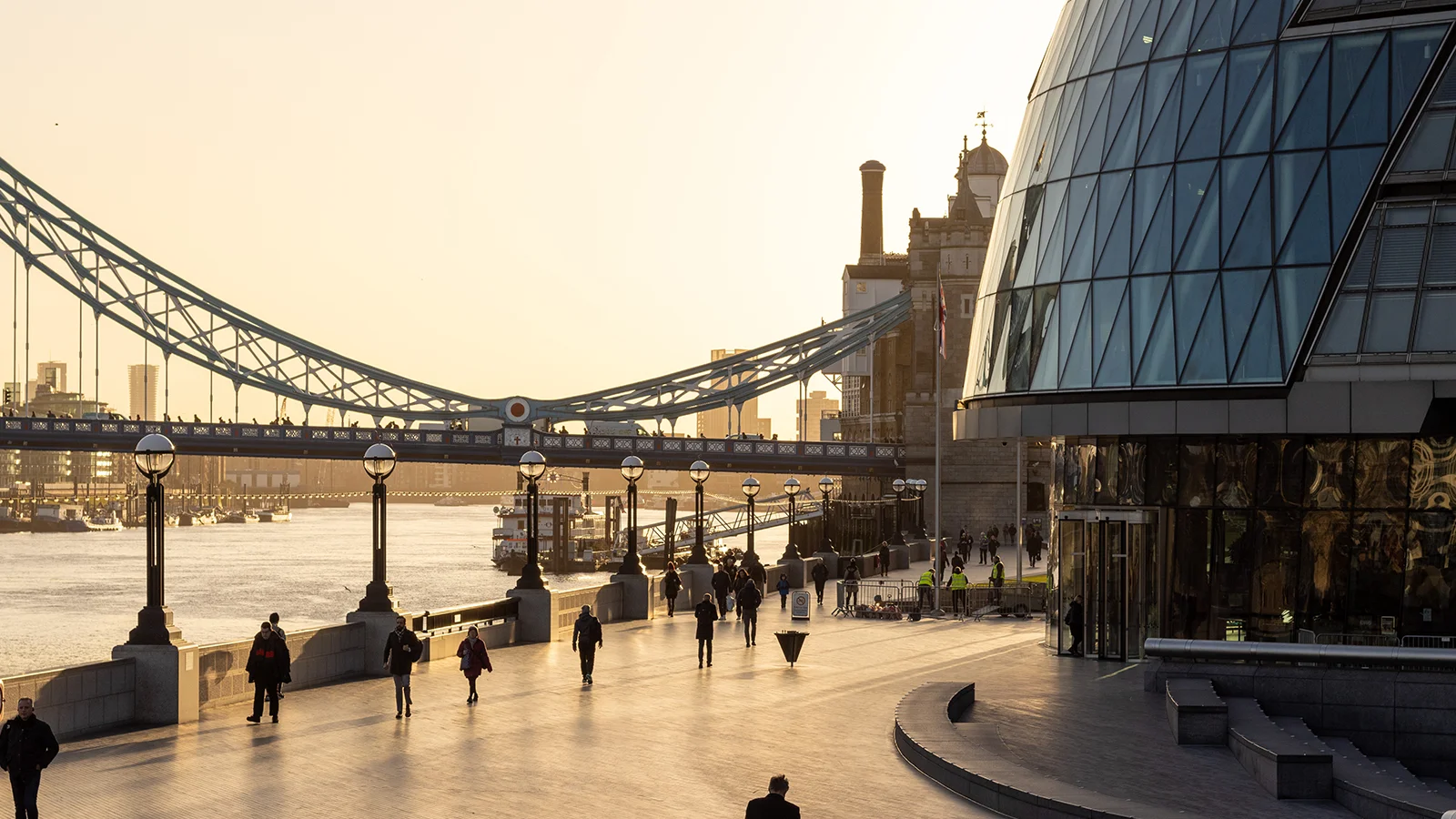 Golden hour view of Tower Bridge and modern glass City Hall beside River Thames