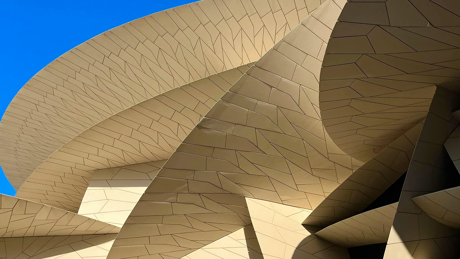 Abstract architectural close-up of beige metal cladding with sweeping curved lines