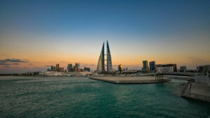Bahrain World Trade Center towers beside waterfront with city skyline at sunset
