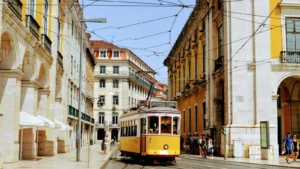 Classic Lisbon tram on cobbled street, surrounded by pastel buildings and pedestrians