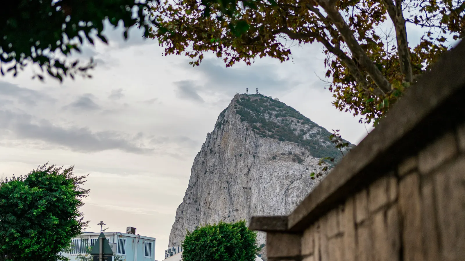 Limestone Rock of Gibraltar towering over town with cloudy sky and greenery