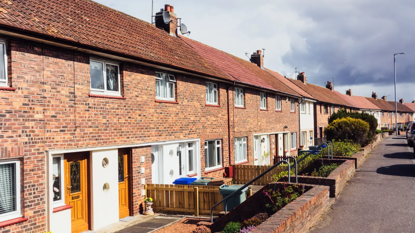 Traditional brick houses with tiled roofs and chimneys under cloudy sky