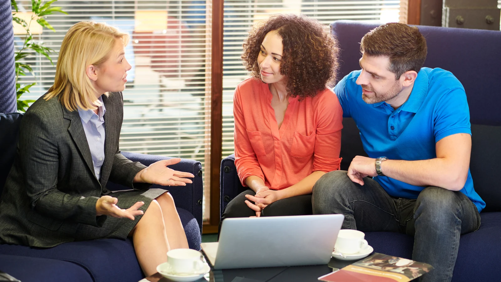 Woman in suit speaking with couple in office lounge setting