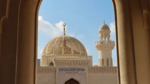 Oman mosque dome with crescent finial and minaret framed by large stone arch