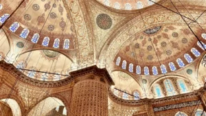 Grand Ottoman mosque ceiling featuring detailed motifs, curved arches, and bright stained-glass windows