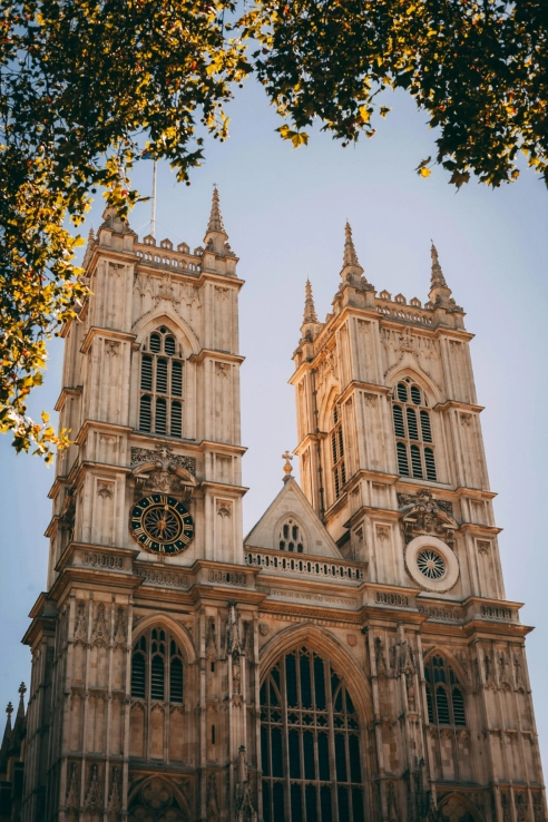 Twin Gothic towers of Westminster Abbey framed by autumn tree branches against a clear sky