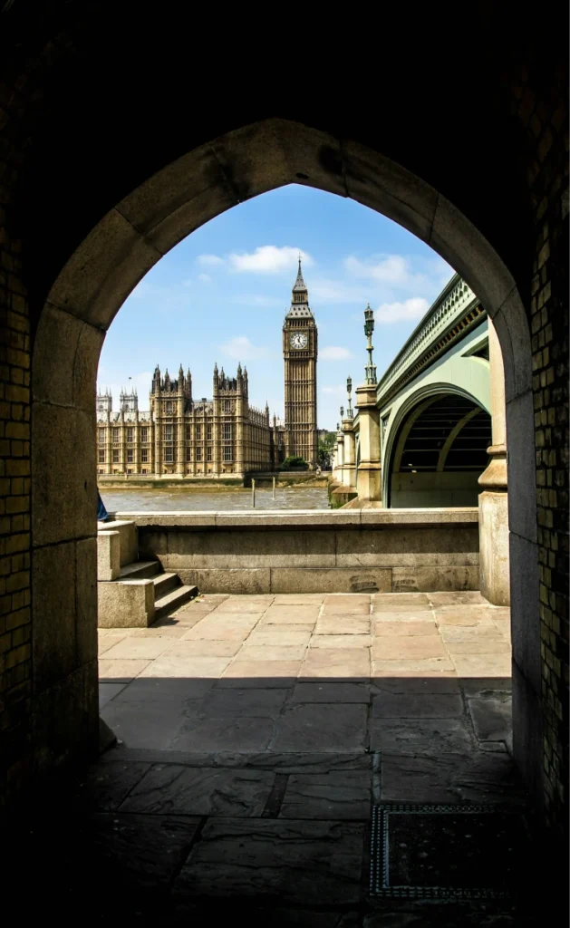 Big Ben and the Houses of Parliament viewed through a stone archway beside Westminster Bridge