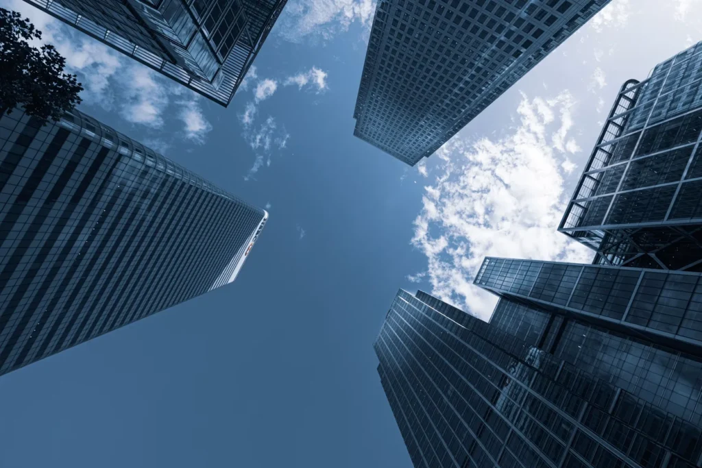 Low-angle view of glass office skyscrapers reaching into a blue sky