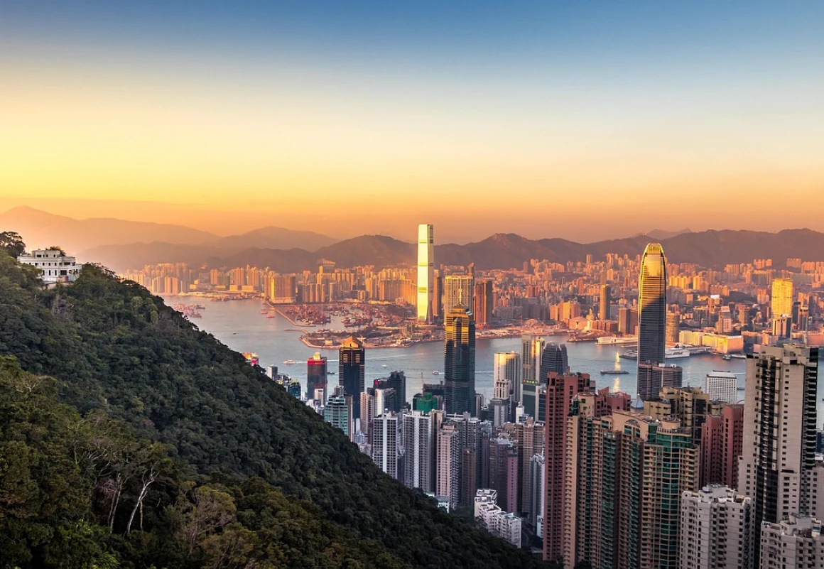 Hong Kong skyline at sunset from Victoria Peak, with dense high-rise towers and Victoria Harbour beyond