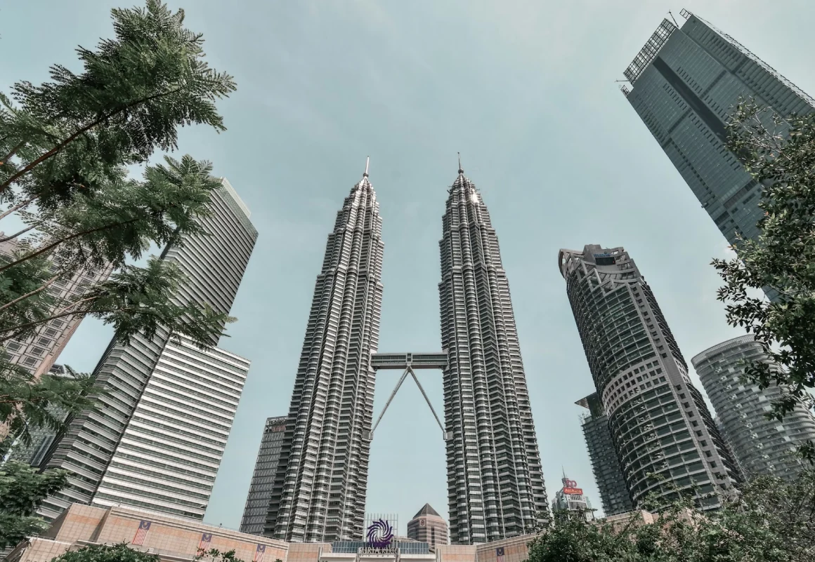 Petronas Twin Towers rising above Kuala Lumpur, viewed from below between other skyscrapers