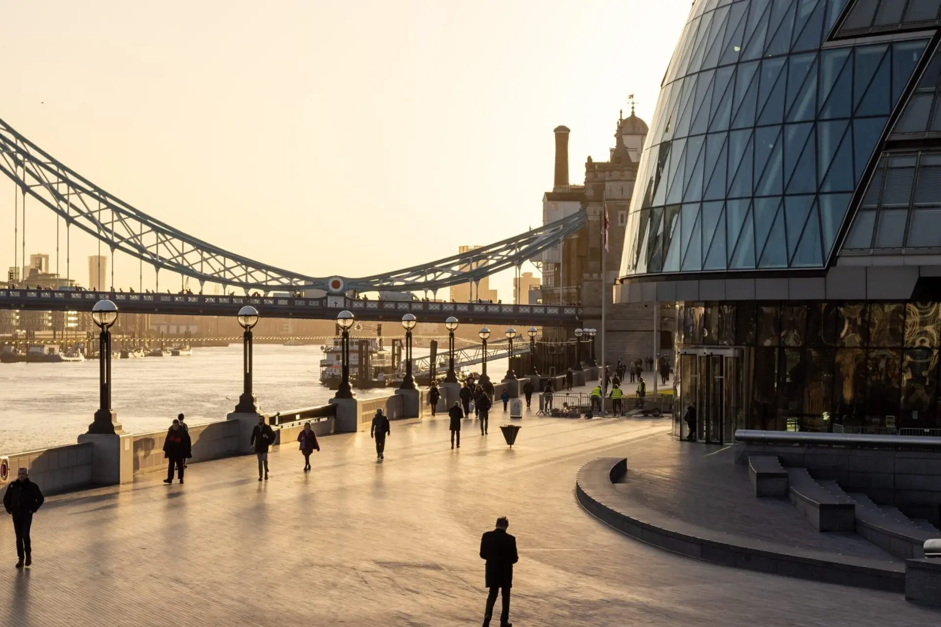 Tower Bridge and the riverside walk beside City Hall at sunset with a lone figure