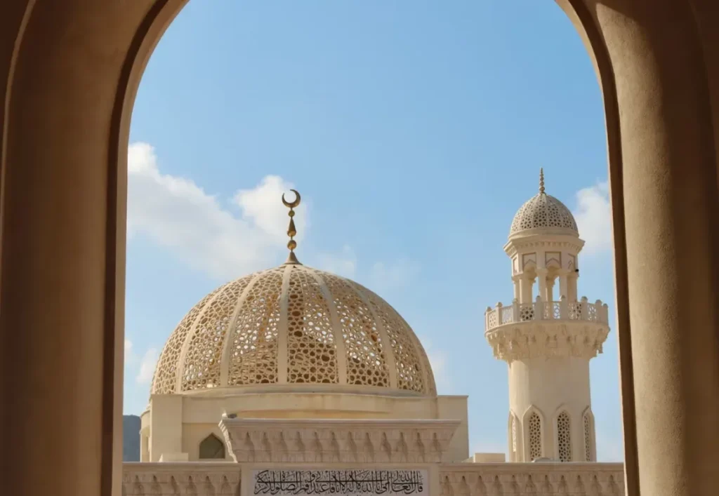Mosque dome and minaret framed by an arch in Oman