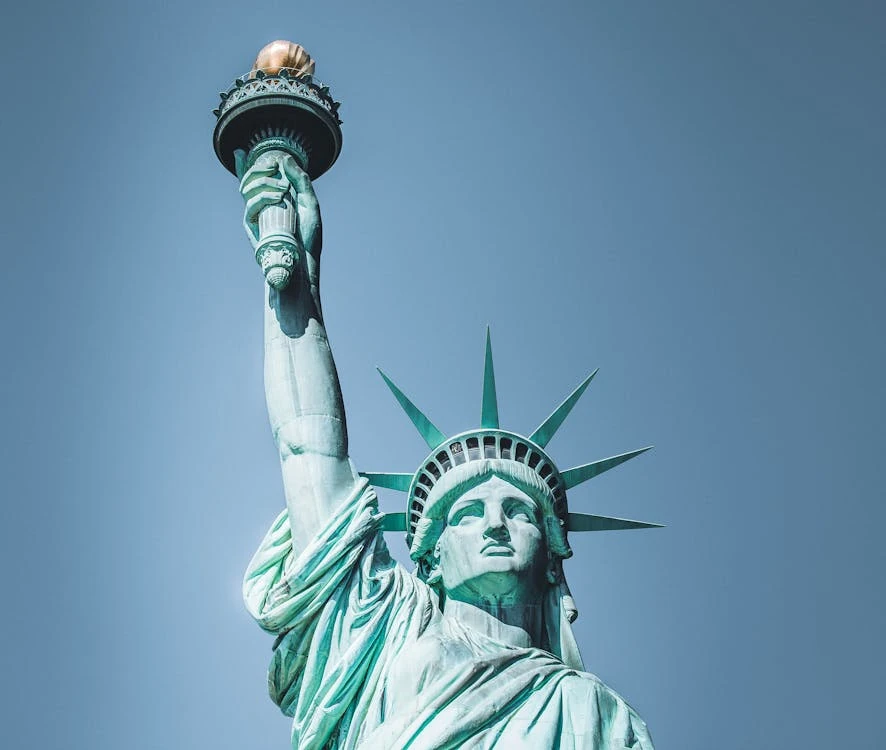 The Statue of Liberty against a clear blue sky, holding its torch aloft