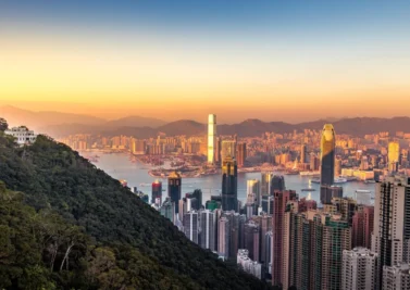 Hong Kong skyline at sunset from Victoria Peak, with dense high-rise towers and Victoria Harbour beyond