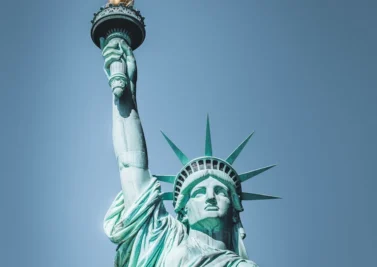 The Statue of Liberty against a clear blue sky, holding its torch aloft